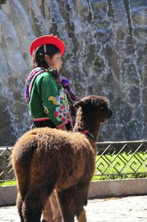 Cusco - Inka-Mädchen mit Alpaca : Ein kleines Inka-Mädchen steht mit einem jungen Alpaca vor einer Mauer. Aufgenommen am 30. August 2011 in der einstigen Inka-Hauptstadt Cusco