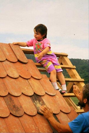 Detail vorheriges Bild: Kind beim Dach decken am Spielhaus