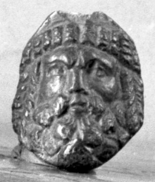 Bärtige Maske, die Haare über der Stirn und an den Seiten steif symmetrisch geordnet