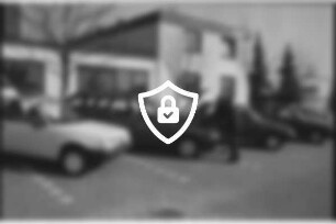 Autohaus [Name maskiert] Gänseberg: Peugeot-Vertragshändler: Parkplatz: Kraftfahrzeugmeister Hans-Joachim Schmelling an geöffneter Motorhaube von Peugeot-Pkw: gibt Erklärungen an Kunde: daneben Pkws: 19. März 1990