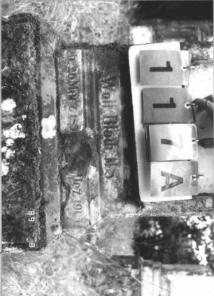 Grabstein 117 (Index: 99800084) Material: Sandstein Zustand: verwittert, linke Seite abgeschlagen, Originalschriftplatte fehlt Maße HxBxT: 124x47x21 cm Beschreibung: Stele, Giebelabschluß mit Verdachung, rechteckige unbeschriebene Ersatzplatte eingelassen, getreppter Sockel: Grabstein 117A