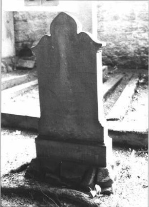 Grabstein 32 (Index: 100105720) Material: Sandstein Zustand: sehr stark verwittert Maße HxBxT: 87x37x8 cm Beschreibung: Stele, Sockel auf Rustica, Abschluß Sonderform Symbolik: sechszackiger Stern und florales Motiv Besonderheit: Kindergrab: Grabstein 32