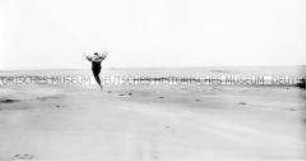 Rückenansicht einer am Strand springenden Person