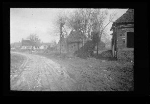 Bus (Dep. Pas-de-Calais, Frankreich): morastige "Dorfstraße" neben verlassenen, kleinen Gebäuden