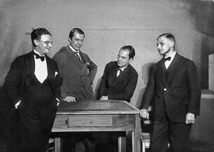 Gruppenporträt Josef Gielen, Georg Brandt, Adolf Mahnke und Franz Jung : Regisseur Josef Gielen, Maschineriedirektor Georg Brandt, Bühnenbildner Adolf Mahnke und Autor Franz Jung anläßlich der Uraufführung von dessen Schauspiel "Legende", Staatsschauspiel Dresden 13.10.1927. Aufnahme im Bühnenbild "Wohnküche Richter". Fotografie (Negativabzug auf Papier) von Ursula Richter
