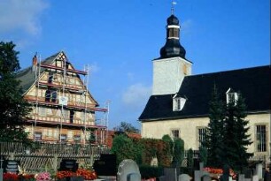 Blick auf die Kirche und das Pfarrhaus, an dem ein Gerüst steht