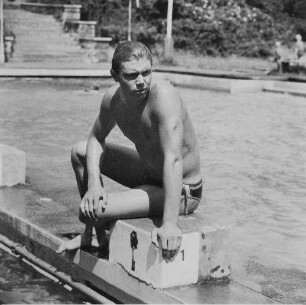 Freibad. Schwimmer auf einem Startblock sitzend