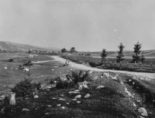 Landschaft : Ein Weg in einer ebenen Landschaft, der zu einem Dorf im Hintergrund führt