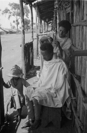 Mann der Amhara : Mann der Amhara lässt sich von einer Frau die Haare schneiden.
