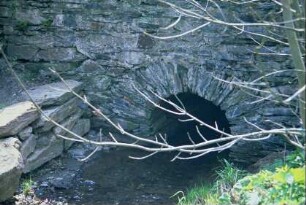 aus Naturstein gesetzte Brücke an einem Bachlauf