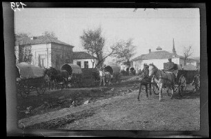 Odobești (=Rumänien): Zweispänner mit Planwagen und Leiterwagen auf beiden Seiten eines Bachbetts, im Hintergrund Gebäude ("Ortschaft")