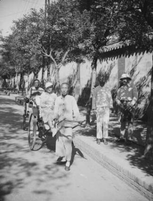 Reise nach China. Peking. Konzessionsviertel : Straßenbild mit der Frau des Fotografen in einer Rikscha