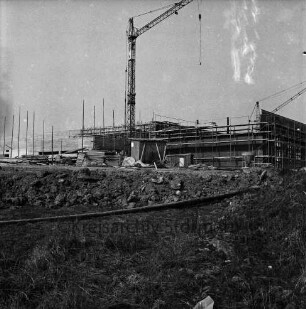 Grund- und Hauptschule am Masurenweg: Masurenweg: Neubau: Schulgebäude im Bau mit Gerüst und Baukran: davor Baumaterial, Baubuden und Bretterstapel: vorn unbefestigtes Gelände: 24. März 1973