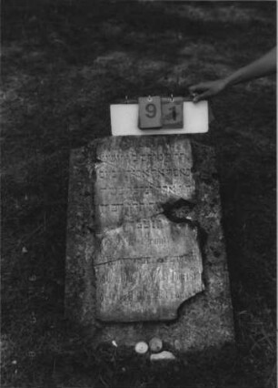 Grabstein 91 (Index: 100113879) Zustand: . . . mit Platte, Platte in mehrere Teile zerbrochen mit Textverlust, repariert Maße HxBxT: 80x52x8 cm Beschreibung: Pultstein: Grabstein 91