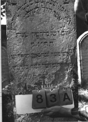 Grabstein 83 (Index: 99786940) Zustand: unteres Drittel stark verwittert Maße HxBxT: 115x44x13 cm Besonderheit: kulturhistorisch wertvoll / hist.-wiss. Gründe (Gemeindestellung): Grabstein 83A