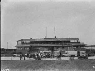 Auf der AVUS : Menschen auf der AVUS, versammelt neben den Expeditionsfahrzeugen Schomburgk´s vor einem Gebäude an der AVUS.