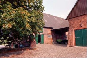 Fritz-Berodt-Straße 7-9: Hofanlage: westliches Wirtschaftsgebäude, Traufseite, mit Tor: Hofüberbauung zum östlichen Wirtschaftsgebäude, Giebelseite mit Lisene, Tor, darüber Fassadenplastik Pferdekopf, Giebel mit Verbretterung: davor Hofplatz mit Kopfsteinpflaster, Hofmauer mit Geländer: Baum: 19. August 1993