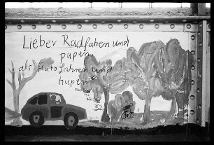 Brückengeländer mit Inschrift "Lieber Radfahren und pupen als Auto fahren und hupen"