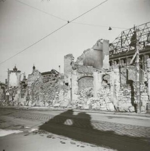 Blick über Gebäudereste und gestapelte Steine gegen Ruine der Reformierten Kirche und Neues Rathaus