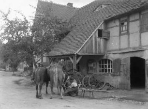 Dorfschmiede : Hufschmiede beim Beschlagen der Hufe vor der Schmiede