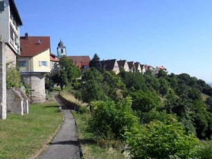 Stadtbefestigung - Ansicht im Südosten mit Stadtmauerverlauf und neuzeitlich aufgebauten Häusern über Flanke zum Tal