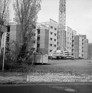 Lottbek: Neubausiedlung: Wohnungsbau: vorn Gehweg: dahinter links Büsche und Bäume sowie Bauschild: dahinter Baucontainer: hinten Mitte Baukran: dahinter Wohnblocks im Bau