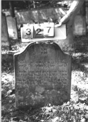Grabstein 327 (Index: 99609964) Material: Sandstein Zustand: stark verwittert, eingesunken, weitgehender Textverlust Maße HxBxT: 56x46x8 cm Beschreibung: Stele, geschwungener eingezogener Korbbogenabschluß, Schriftfeld erhaben: Grabstein 327