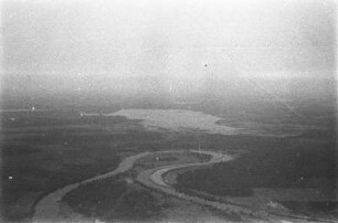 Luftbildaufnahme der Seenlandschaft : ebene Landschaft. Im Hintergrund ein See. Im Bildvordergrund ein sich mäandernder Fluss.