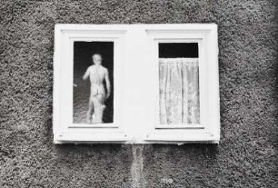 Fenster mit Gardine und kleiner Statue des David