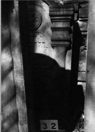 Grabstein 32 (Index: 99629533) Material: Sandstein Zustand: stark verwittert Maße HxBxT: 123x64x11 cm Beschreibung: Stele mit eingezogenem Rundbogenabschluß, zwei Halbsäulen Symbolik: Kranz um Levitenkanne: Grabstein 32