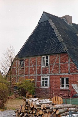 Schulstraße (10): Bauernhaus aus Fachwerk: Giebelseite Wohntrakt: Stapel mit Baumstämmen