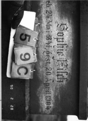 Grabstein 59 (Index: 100114889) Material: Sandstein und polierter Granit Zustand: Textplatte mehrfach zerbrochen, repariert mit kleinem Textverlust Maße HxBxT: 269x70x32 cm Beschreibung: Ädikula mit gestuftem Sockel auf Rustikasockel, überstehender, eingezogener Spitzgiebel mit floralem Dekor, eingesetzte Textplatte: Grabstein 59C