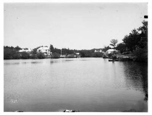 Bermudainseln. Küstenlandschaft. Blick in eine Bucht mit Bootsanlegestelle und hellen Wohnhäusern