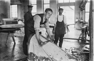 Freiberg-Zug, An der Zugspitze 42. Lederfabrik Zug. Werkteil Zugspitze. Gerberei. Gerber beim Entfleischen mit traditionellen Werkzeugen (Scherdegen und Gerberbaum)