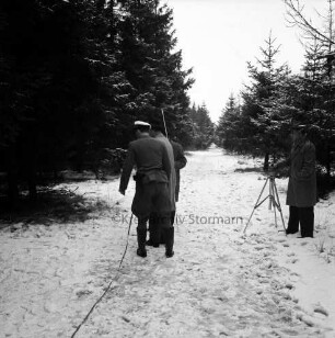 Polizei: Mord an der Hamburger Küchenhilfe Edeltraut Harloff am 26. November 1965: Oher Tannen: Leichenfundort zwischen Tannen und Totholz: in der Mitte Gruppe von Polizeibeamten der Lübecker und der Hamburger Mordkommission auf Weg: rechts Polizeifotograf an Fotostativ: hinten Tannen: Winter