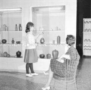 Besucher der Ausstellung zum Kunsthandwerk in der DDR betrachten Vasen und Gefäße