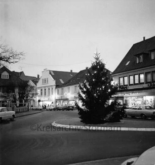 Besttorstraße Ecke Bahnhofstraße: Tannenbaum mit Adventsbeleuchtung auf der Verkehrsinsel, dahinter parkenden Pkws und Gebäuden mit Adventsbelechtung, links die Besttorbrücke, Blick Richtung Nordwesten