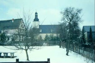 Blick auf die Kirche, links Pfarrhaus, vorn Spielplatz