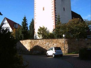 Ansicht von Nordosten mit Kirchturm (Schlüsselloch-Schießscharten im Mittelgeschoß) über Kirchhofmauer (Wehrgang mit Steinbrüstung im 19 Jh abgetragen) in übersichtlichem Verlauf