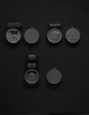 Drei Medaillen der DDR, Avers und Revers. Oben links: Orden Kämpfer gegen die Reaktion 1918-1923 ((Medaille für Teilnahme an den bewaffneten Kämpfen der deutschen Arbeiterklasse in den Jahren 1918-1923); 32 mm Durchmesser) an Spange. Oben rechts: Medaille für Kämpfer gegen den Faschismus 1933 bis 1945 (versilbert; 32 mm Durchmesser; 1958 gestiftet) an Spange (24 mm breit). Unten: Verdienstmedaille der DDR (versilbert; 33 mm Durchmesser; 1959 gestiftet) an Spange (11 x 24 mm) inklusive Interimsspange
