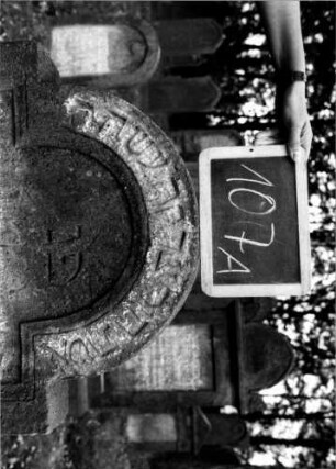 Grabstein 107 (Index: 100111221) Material: Sandstein Zustand: verwittert Maße HxBxT: 120x69x14 cm Beschreibung: Stele, eingezogener Rundbogenabschluß, Schriftfeld eingetieft: Grabstein 107A