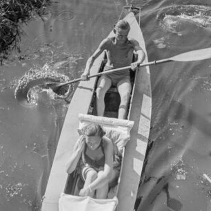 Ein Mann und eine Frau in Badebekleidung sitzen in einem Paddelboot