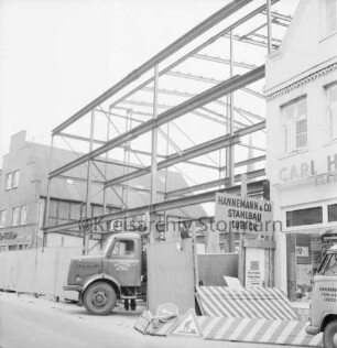 Firma Carl Hoffmann: Hindenburgstraße: Elektrohandel: Neubau: Aufbau des Stahlgerüsts: vorn Bauzaun, Lkw und Absperrung: rechts und links Wohn- und Geschäftshäuser mit Haushaltswarengeschäft Otto Möller und Elektrogeschäft Carl Hoffmann