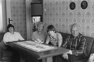 Familie F. (Lohnbuchhalterin, Montagemeister, Töchter: Ingenieurin, Vorpraktikantin) im Wohnzimmer