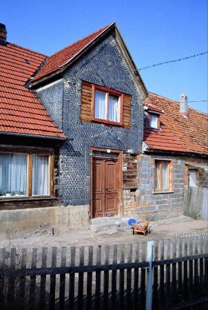 einstöckiges Wohnhaus mit verschiefertem Zwerchhaus; Schieferornamente um Tür und Fenster