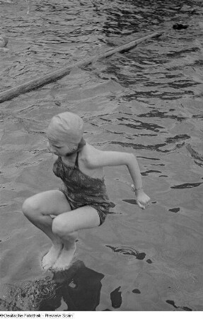 Mädchen beim Sprung ins Schwimmbecken eines Freibades