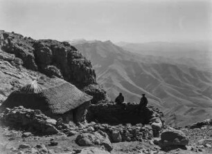 Bergstation : Steinhaus einer Bergstation in den Drankensbergen ("Drachenberge"). Auf einer Mauer sitzen zwei Männer