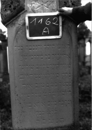 Grabstein 1162 (Index: 100104288) Material: Sandstein Zustand: stellenweise leicht verwittert Maße HxBxT: 190x51x22 cm Beschreibung: Stele auf getrepptem Sockel, giebelartiger, rechteckiger erhöhter Abschluss mit Verdachung, Eck- und Giebelakroterien (Akanthus u. a. Blattornamente), eingetieftes, rundbogiges Schriftfeld, darüber ein eingeritzer Stern Symbolik: Akanthus, Blattornamente, Stern: Grabstein 1162A