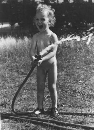 Hamburg-Volksdorf. Sommer. Der Junge (Mimo Moock) kühlt sich mit Wasser aus dem Gartenschlauch ab