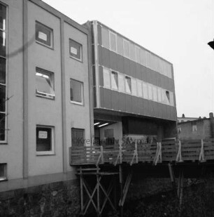 Nickel: Mühlenstraße / Lübecker Straße: Kaufhaus: Erweiterungsbau auf rückwärtigem Grundstück Mühlenstraße: Eröffnung: Außenansicht: Rückfront mit Vollverglasung, Hintereingang, Schaufenster: Fußgängerbrücke über Trave, mit Gerüst: links älterer Kaufhaustrakt Nickel: Aufnahme unscharf